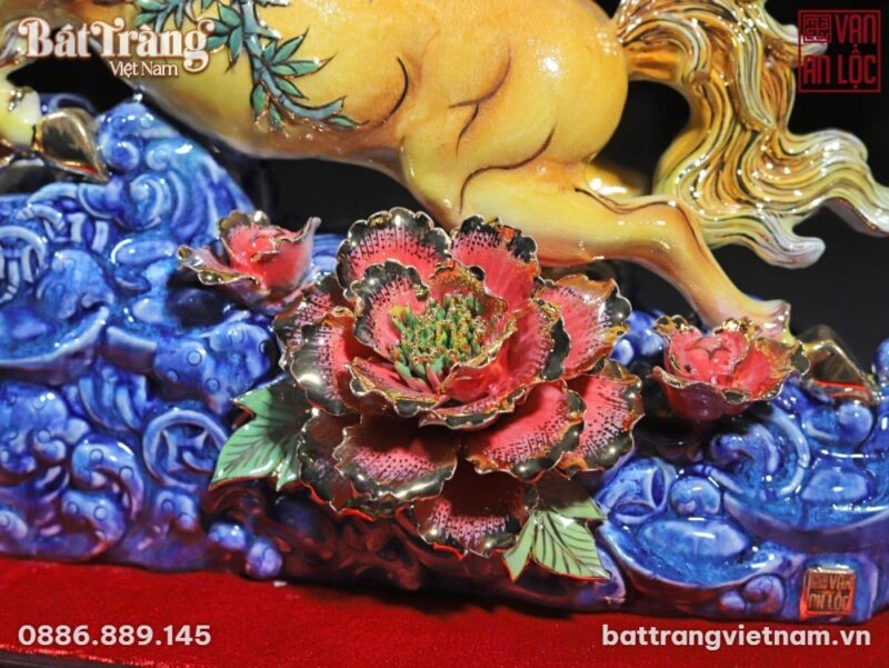Tượng gốm sứ Vạn An Lộc với phần thân sau ngựa vàng óng, đuôi ngựa uốn lượn, và cành tre xanh trên lưng, đang phi trên khối mây xanh dương. Nổi bật phía trước là đóa hoa mẫu đơn đỏ rực rỡ với nhụy vàng và viền cánh dát vàng 24K, đặt trên nền mây xanh tinh xảo, thể hiện sự sang trọng và chi tiết thủ công. Tượng gốm sứ Vạn An Lộc với phần thân sau ngựa vàng óng, đuôi ngựa uốn lượn, và cành tre xanh trên lưng, đang phi trên khối mây xanh dương. Nổi bật phía trước là đóa hoa mẫu đơn đỏ rực rỡ với nhụy vàng và viền cánh dát vàng 24K, đặt trên nền mây xanh tinh xảo, thể hiện sự sang trọng và chi tiết thủ công.